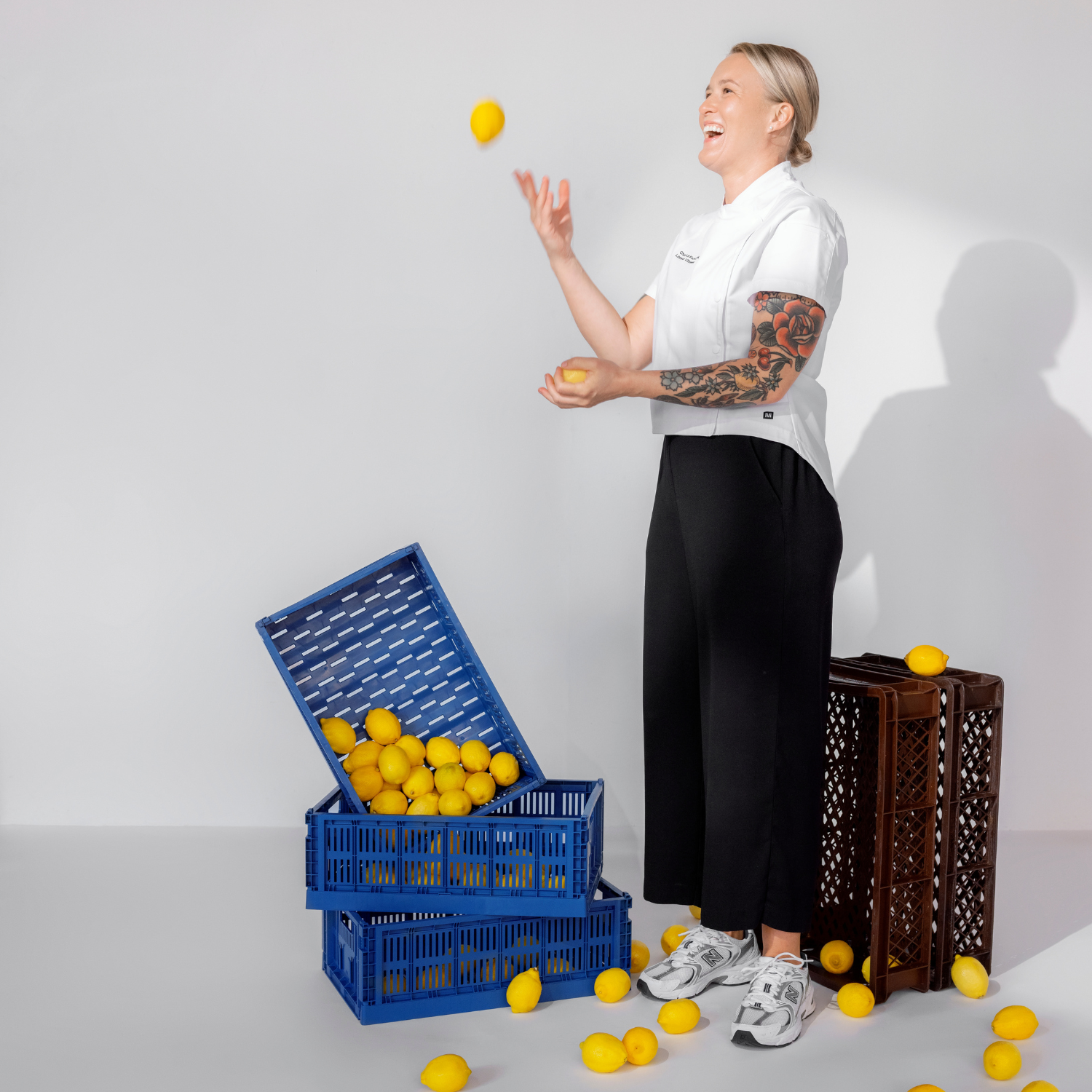 Kokki Linnea Vihonen heittää sitruunoita ilmaan valkoisessa kokkitakissa.