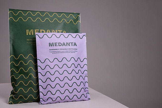 Medantan postituspussit pöydällä, taaempana iso vihreä ja edustalla pienempi violetti pussi