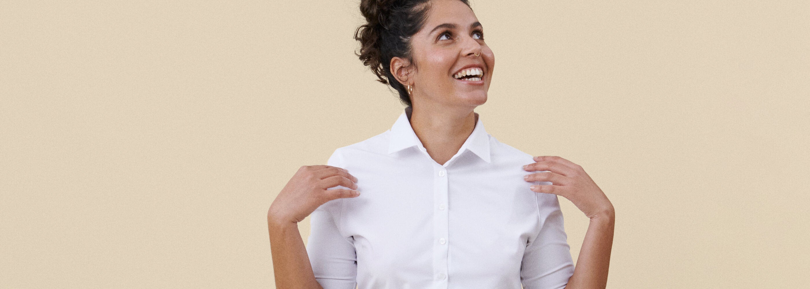 Valkoinen työpaitapusero hymyilevän tarjoilijan päällä, beige tausta.