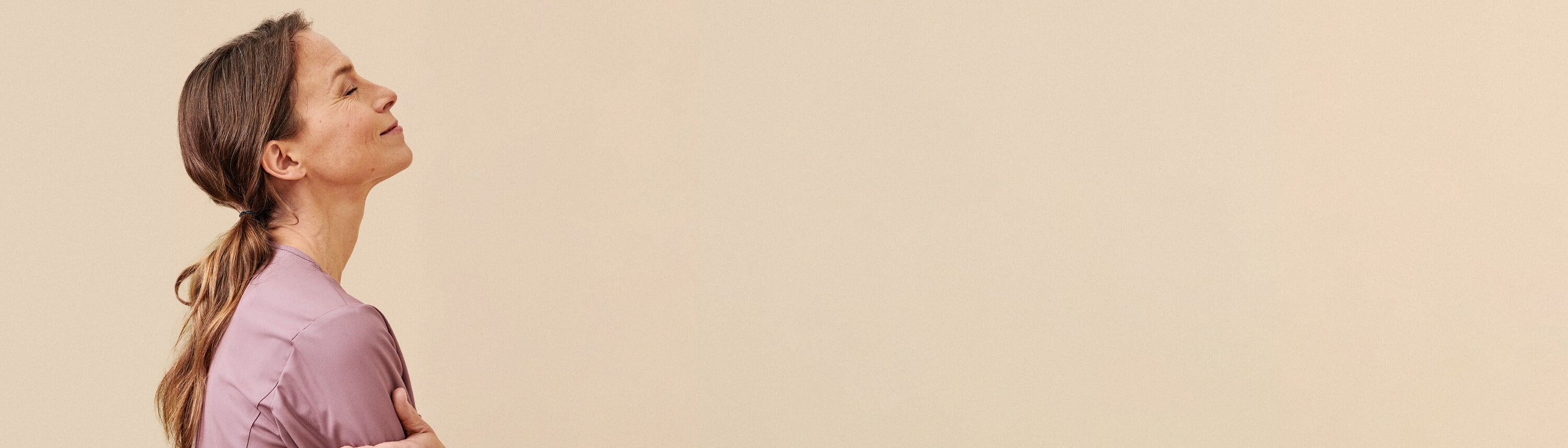 Roosanvärinen työpaita hoitajan yllä, beigellä taustalla