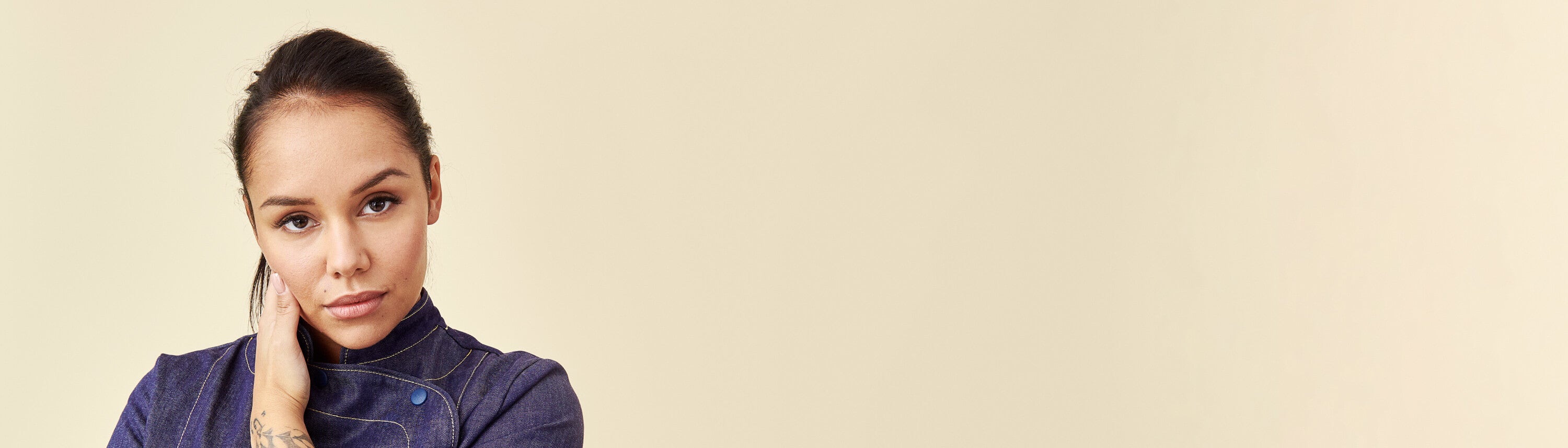 Denim-kokintakki kokin yllä, beige tausta.