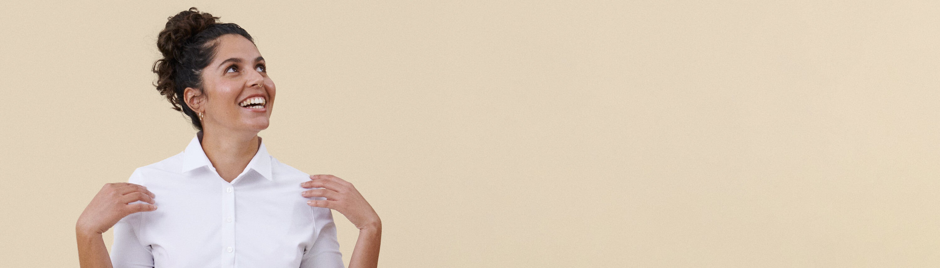 Valkoinen työpaitapusero hymyilevän tarjoilijan päällä, beige tausta.