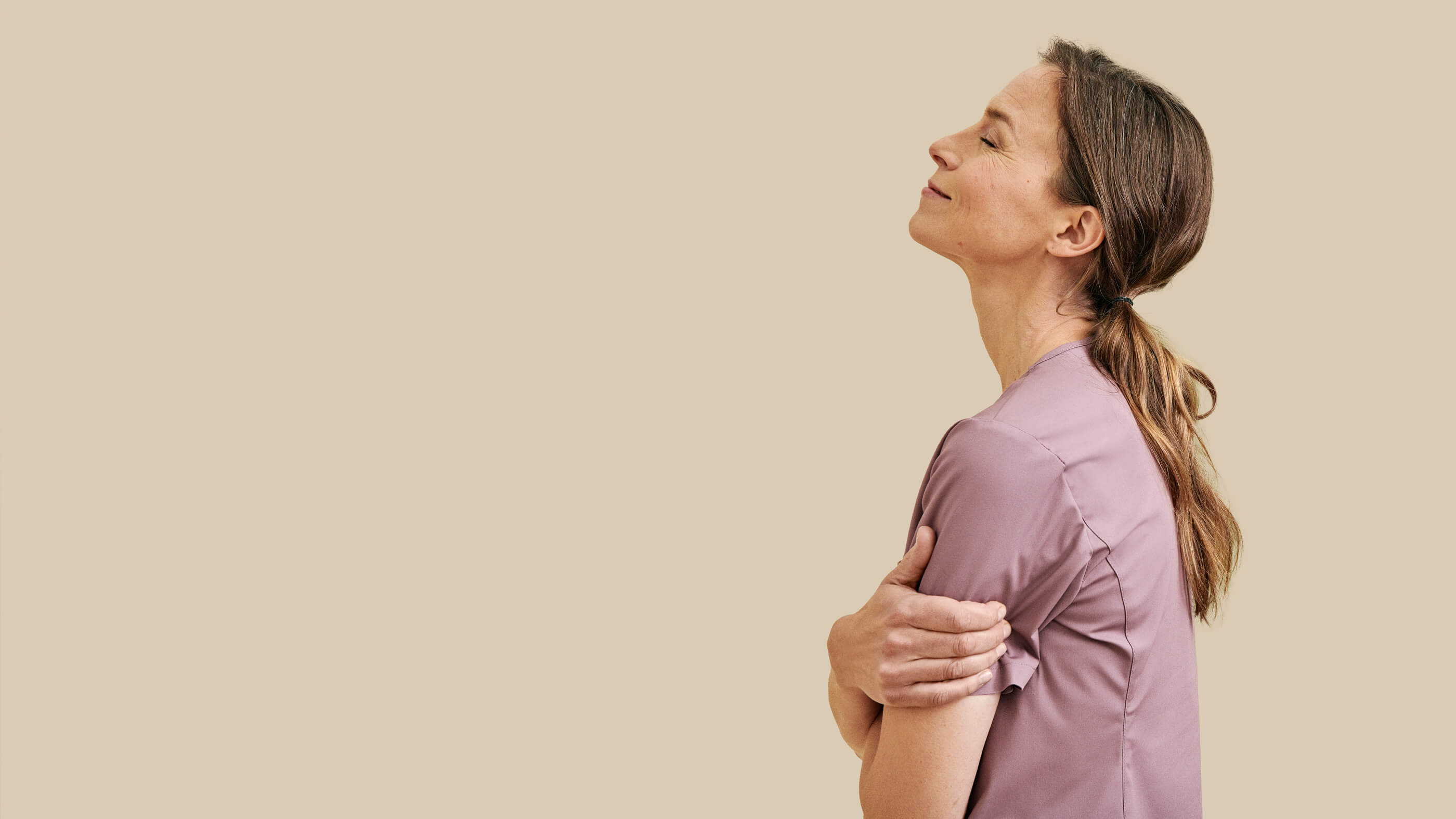 Roosanvärinen työpaita hoitajan yllä, beigellä taustalla