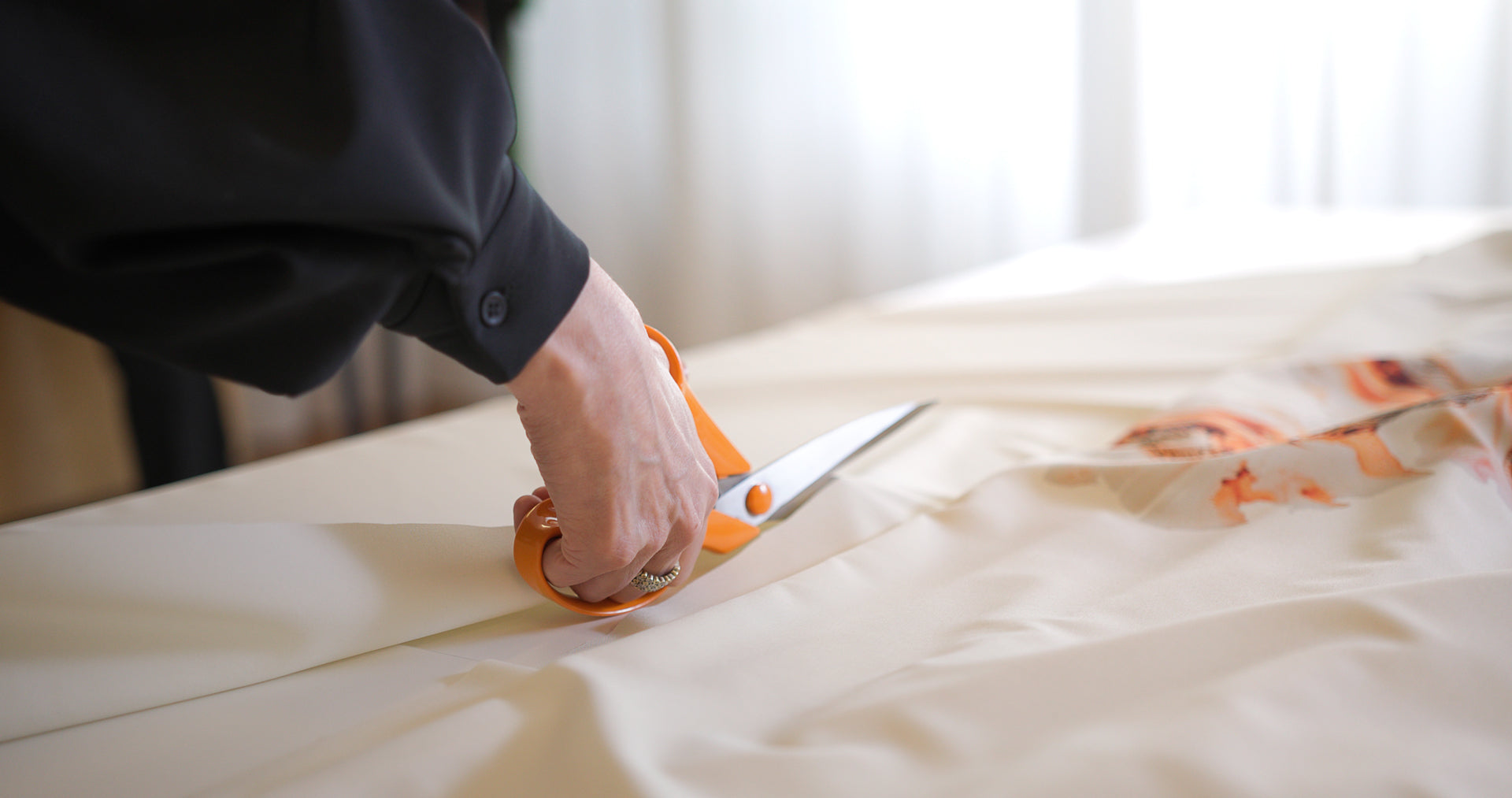 Lähikuva Tainasta leikkaamassa Medantan Lumiere-puvun kangasta
